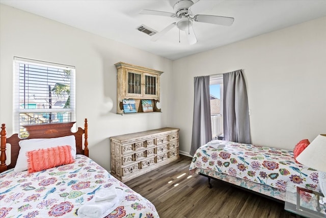 bedroom with multiple windows, dark hardwood / wood-style floors, and ceiling fan