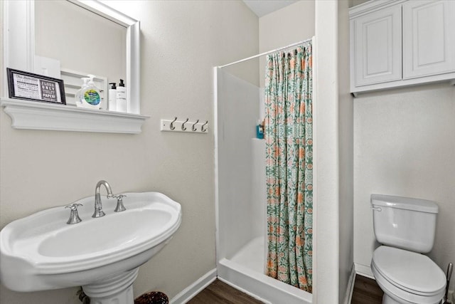 bathroom with baseboards, a stall shower, toilet, and wood finished floors