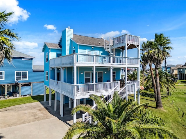 rear view of property with a yard, a carport, and a balcony