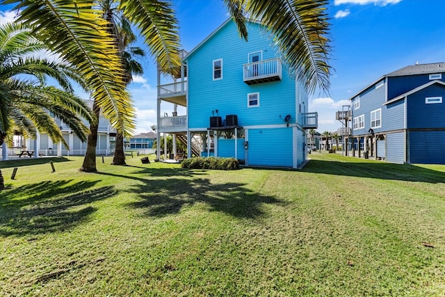 rear view of property featuring a yard, cooling unit, and a balcony