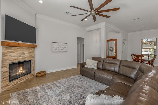 living room with crown molding, a fireplace, ceiling fan with notable chandelier, and hardwood / wood-style floors