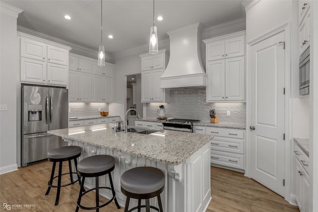 kitchen with a kitchen island with sink, white cabinetry, custom range hood, and appliances with stainless steel finishes