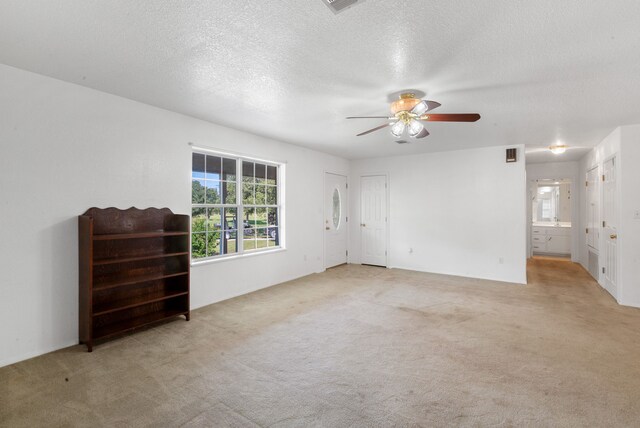 carpeted spare room featuring a textured ceiling and ceiling fan