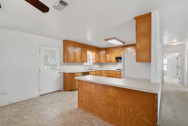 kitchen with kitchen peninsula, sink, light colored carpet, a textured ceiling, and ceiling fan