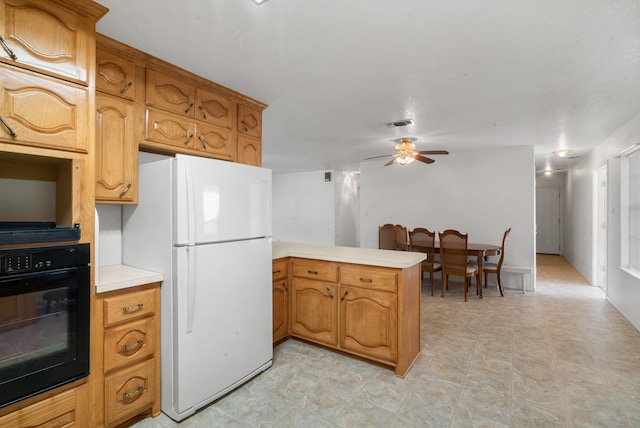 kitchen featuring white fridge, ceiling fan, black oven, and kitchen peninsula