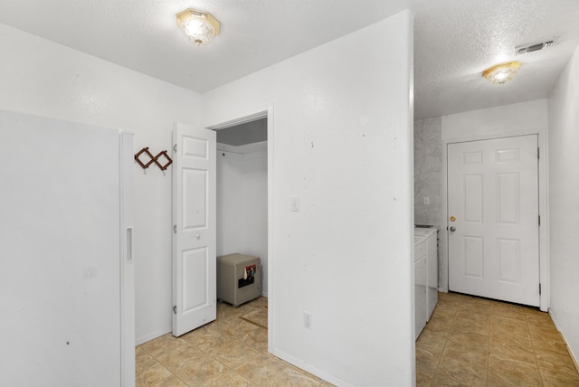 corridor with washer and clothes dryer and a textured ceiling