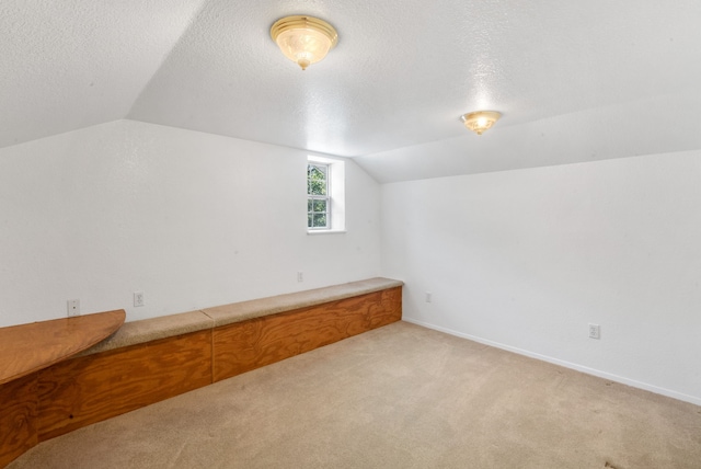 bonus room featuring light carpet, a textured ceiling, and lofted ceiling