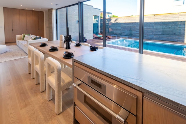 kitchen with light hardwood / wood-style floors, expansive windows, and light brown cabinetry