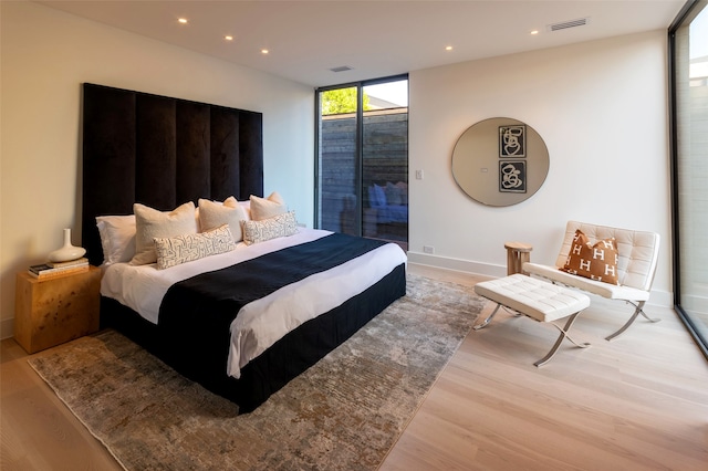 bedroom with expansive windows, multiple windows, and light hardwood / wood-style floors