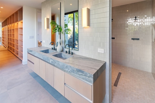 bathroom with tile walls, vanity, a shower, and tile patterned floors