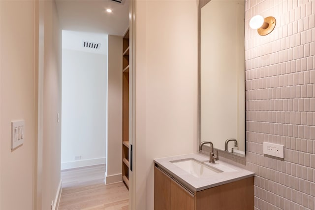 bathroom with tile walls, vanity, and wood-type flooring