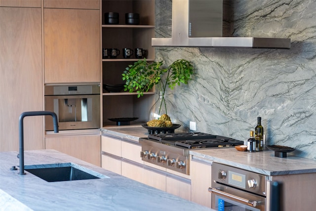 kitchen with light stone countertops, wall chimney range hood, sink, stainless steel appliances, and decorative backsplash