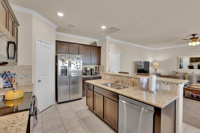 kitchen with a center island with sink, appliances with stainless steel finishes, dark brown cabinets, crown molding, and decorative backsplash