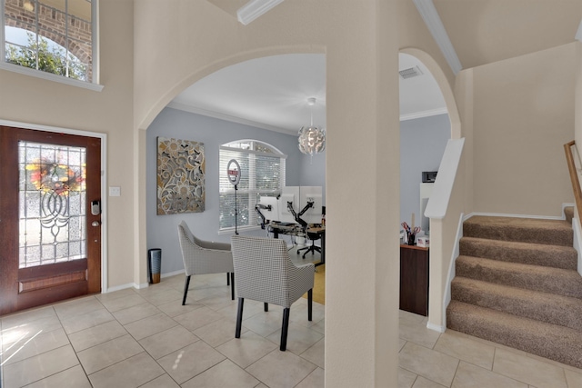 foyer entrance with a chandelier, light tile patterned floors, and ornamental molding