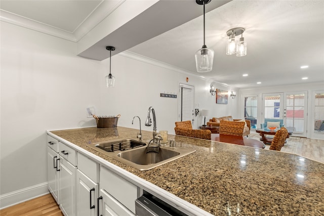 kitchen with sink, light wood-type flooring, pendant lighting, white cabinets, and crown molding