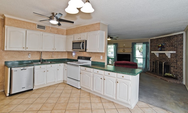 kitchen featuring sink, kitchen peninsula, a brick fireplace, stainless steel appliances, and white cabinets