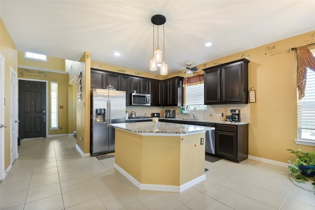 kitchen featuring light stone countertops, hanging light fixtures, stainless steel appliances, and backsplash