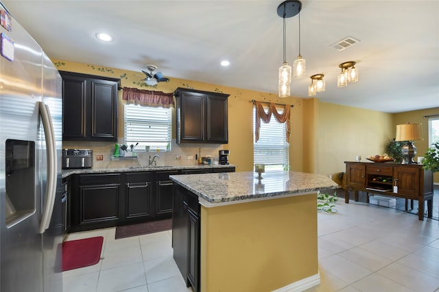 kitchen featuring stainless steel fridge, a healthy amount of sunlight, hanging light fixtures, and a kitchen island