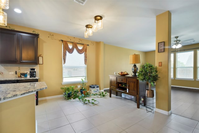 kitchen featuring dark brown cabinets, light stone countertops, tasteful backsplash, light tile patterned floors, and ceiling fan