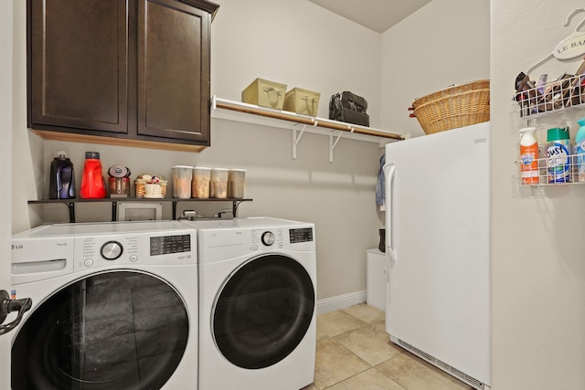 laundry room featuring cabinets, light tile patterned flooring, and washing machine and dryer