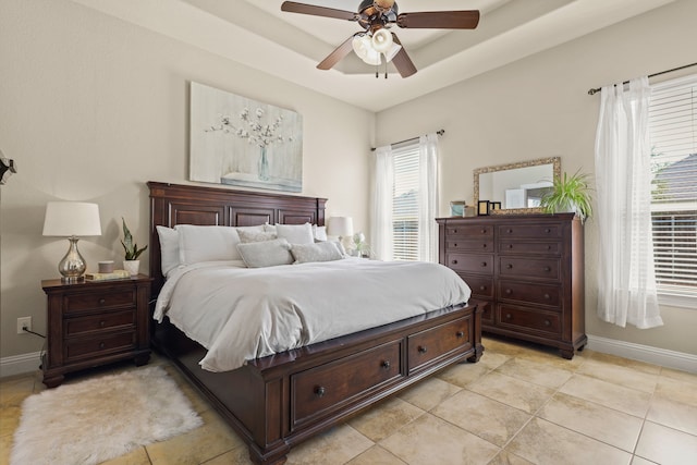 tiled bedroom with ceiling fan and a raised ceiling