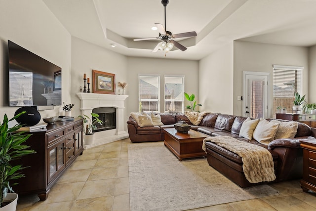 living room with light tile patterned floors, a tray ceiling, and ceiling fan