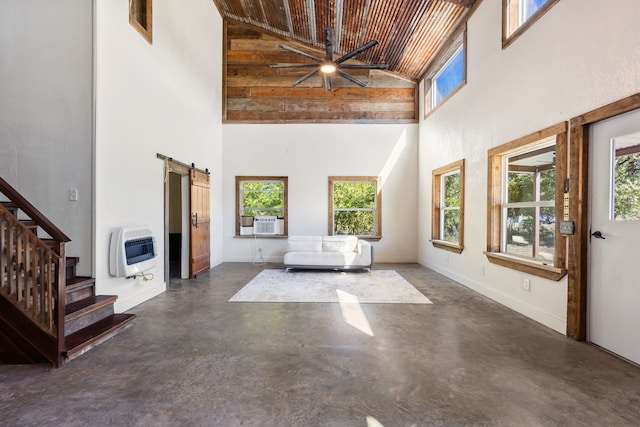 unfurnished living room featuring wood ceiling, heating unit, ceiling fan, a barn door, and high vaulted ceiling