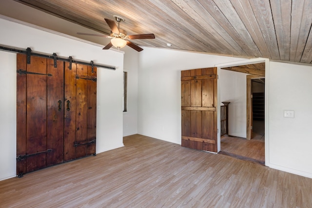 unfurnished bedroom featuring wooden ceiling, vaulted ceiling, a barn door, light wood-type flooring, and ceiling fan