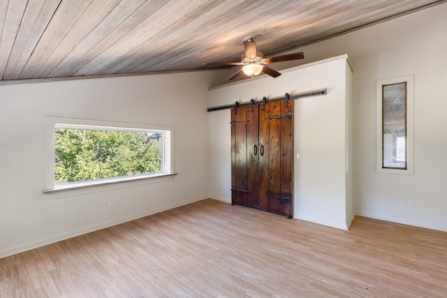 unfurnished bedroom with wood ceiling, ceiling fan, a barn door, vaulted ceiling, and light hardwood / wood-style flooring