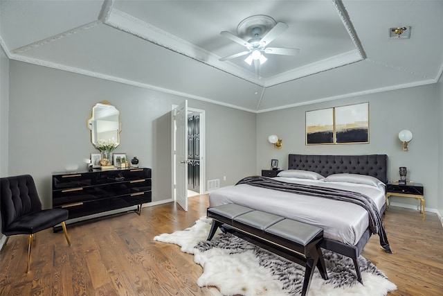 bedroom with hardwood / wood-style floors, a tray ceiling, ceiling fan, and ornamental molding