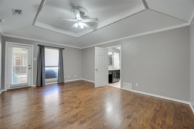 unfurnished room featuring ceiling fan, dark wood-type flooring, a raised ceiling, vaulted ceiling, and ornamental molding