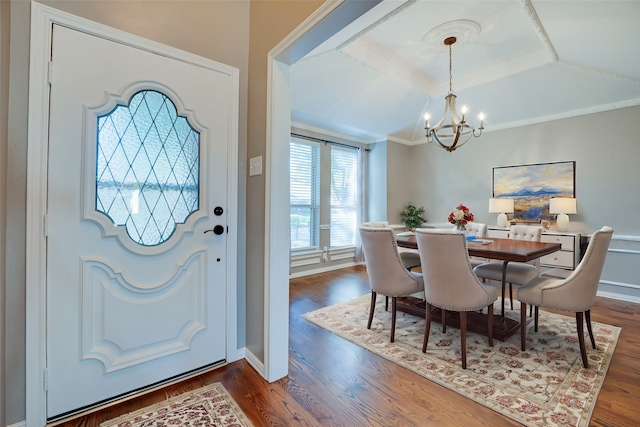 dining area featuring dark wood-type flooring, crown molding, a chandelier, and vaulted ceiling