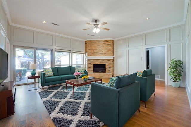 living room featuring a large fireplace, wood-type flooring, and ornamental molding