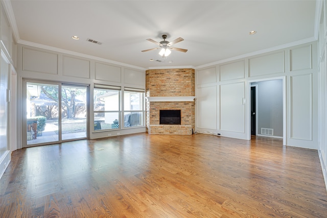 unfurnished living room with a fireplace, hardwood / wood-style floors, ceiling fan, and crown molding