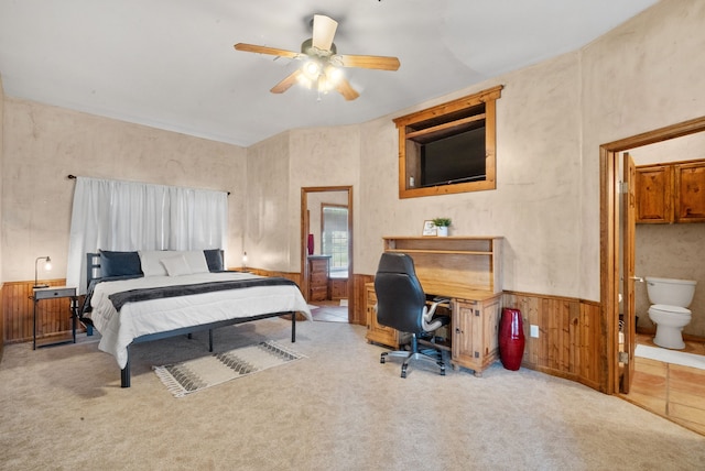 carpeted bedroom featuring wooden walls, connected bathroom, and ceiling fan