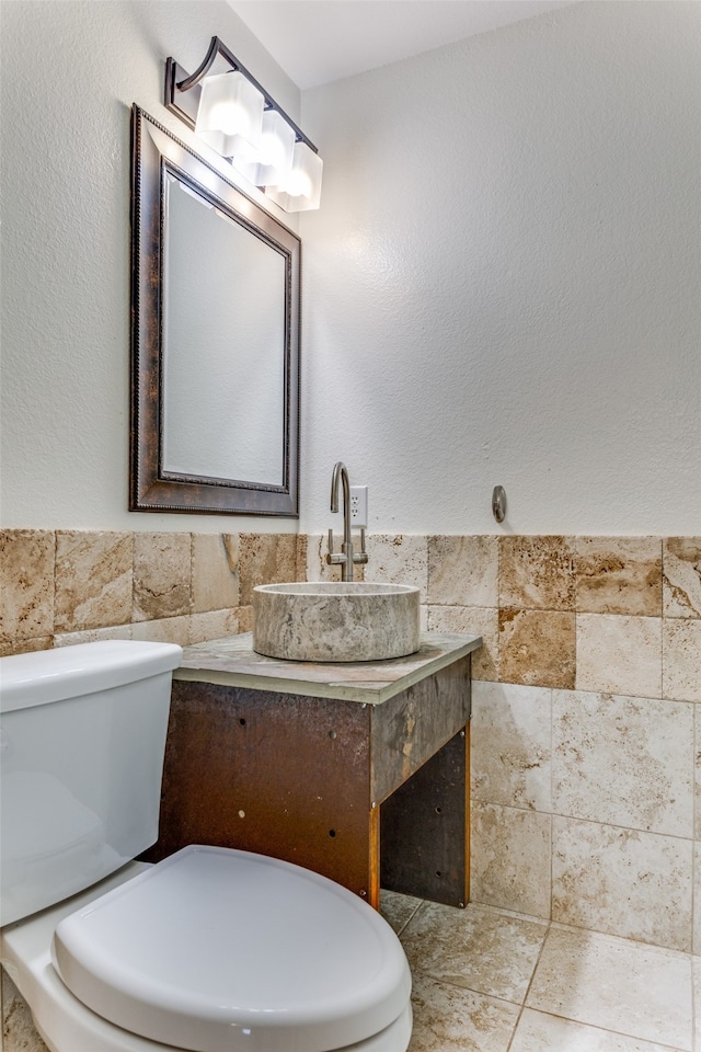 bathroom featuring vanity, toilet, and tile walls