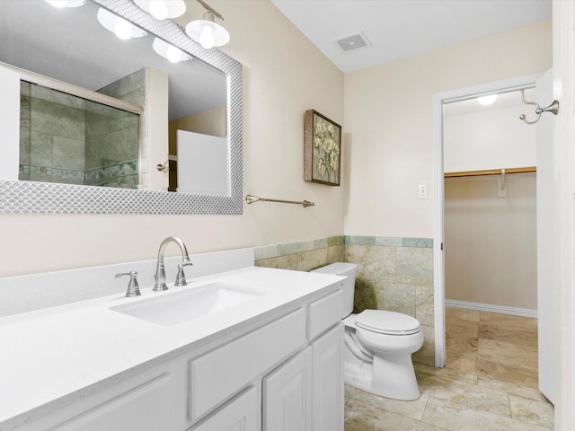1517 Windward Ln, Wylie, TX 75098 - bathroom with a shower stall, tile walls, a walk in closet, toilet, and vanity