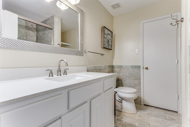 bathroom featuring vanity, toilet, tile walls, and an enclosed shower