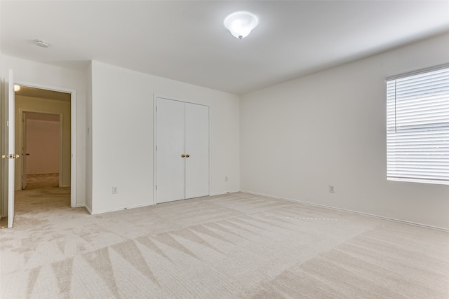 unfurnished bedroom featuring light colored carpet and a closet