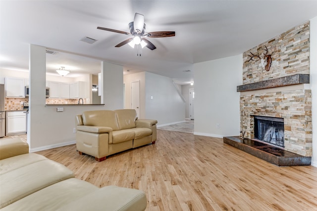 living room with ceiling fan, light wood-type flooring, and a fireplace