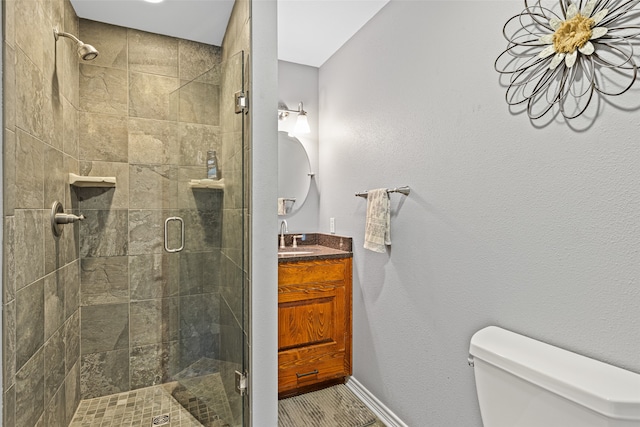 bathroom with toilet, vanity, and a shower with door