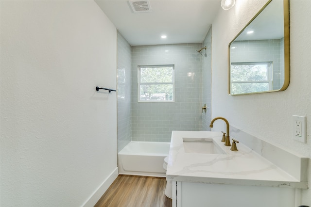 bathroom featuring vanity, tiled shower / bath combo, a healthy amount of sunlight, and wood-type flooring