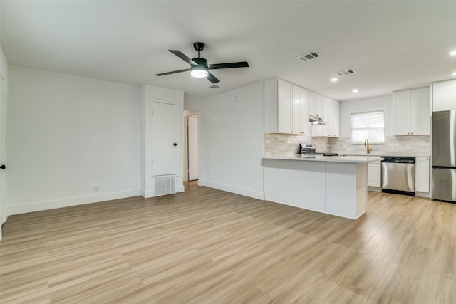 kitchen with kitchen peninsula, stainless steel appliances, light wood-type flooring, and white cabinets