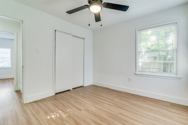 unfurnished bedroom with a closet, multiple windows, light hardwood / wood-style floors, and ceiling fan