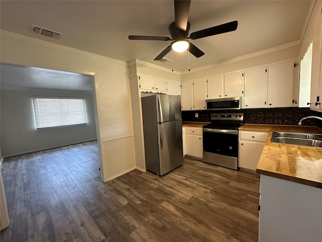 kitchen with appliances with stainless steel finishes, sink, backsplash, white cabinetry, and dark wood-type flooring