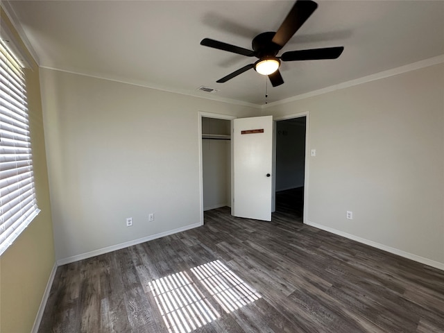 unfurnished bedroom with a closet, dark wood-type flooring, crown molding, and ceiling fan