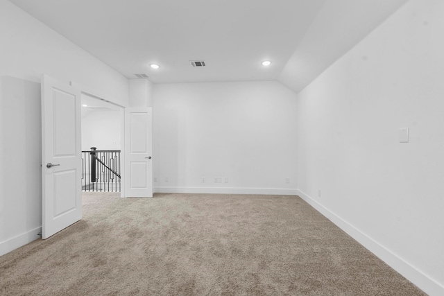 carpeted empty room featuring lofted ceiling