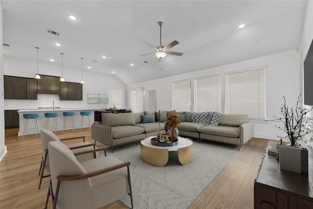 living room with ceiling fan, lofted ceiling, and light hardwood / wood-style flooring