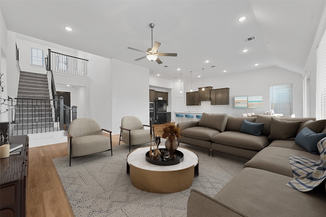 living room featuring ceiling fan, light hardwood / wood-style flooring, and vaulted ceiling