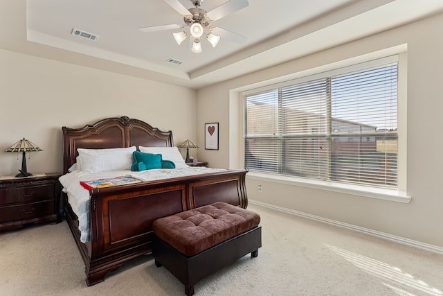 bedroom with light carpet, a tray ceiling, and ceiling fan